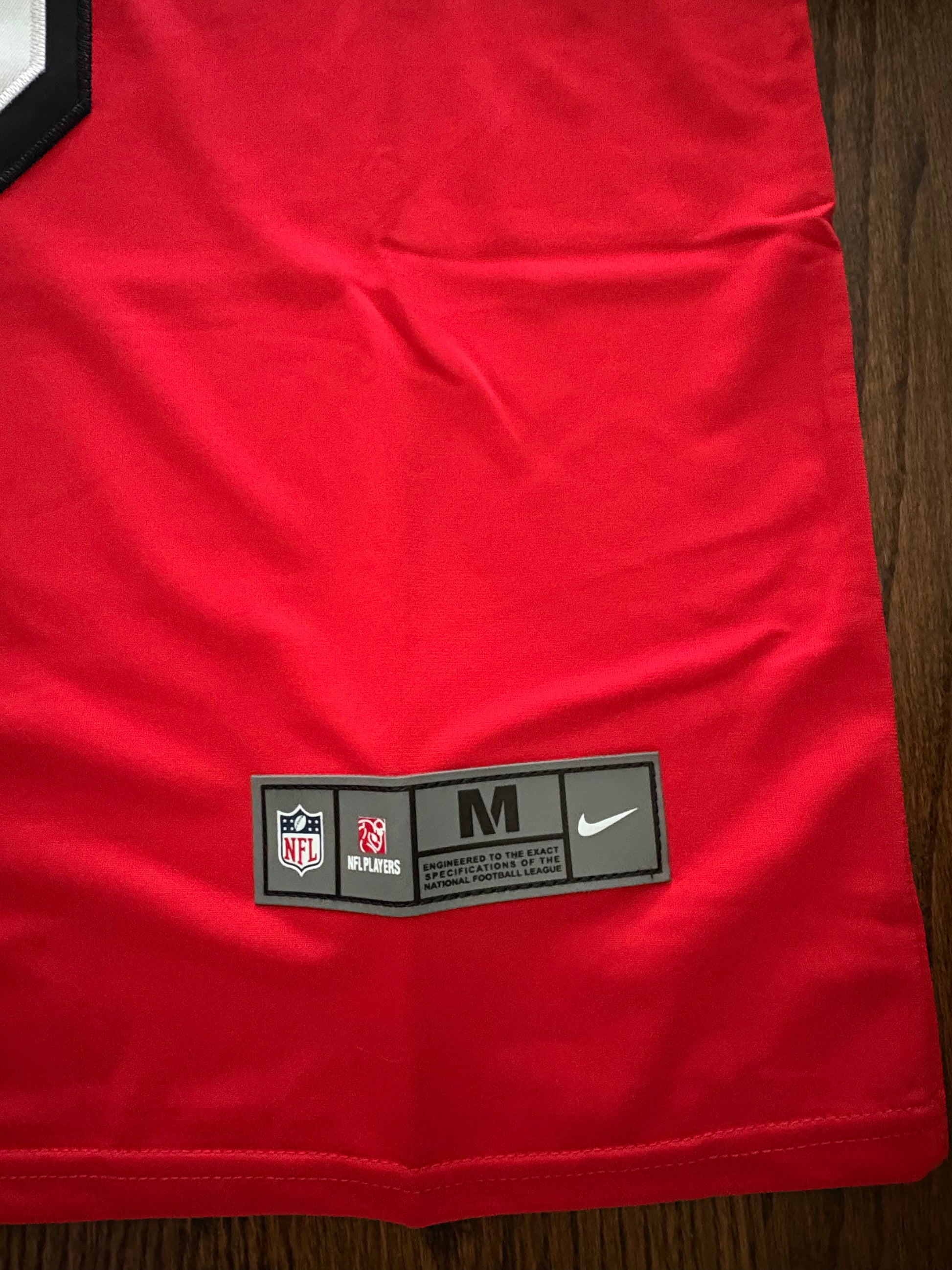 Red sports jersey with a label on a wooden surface