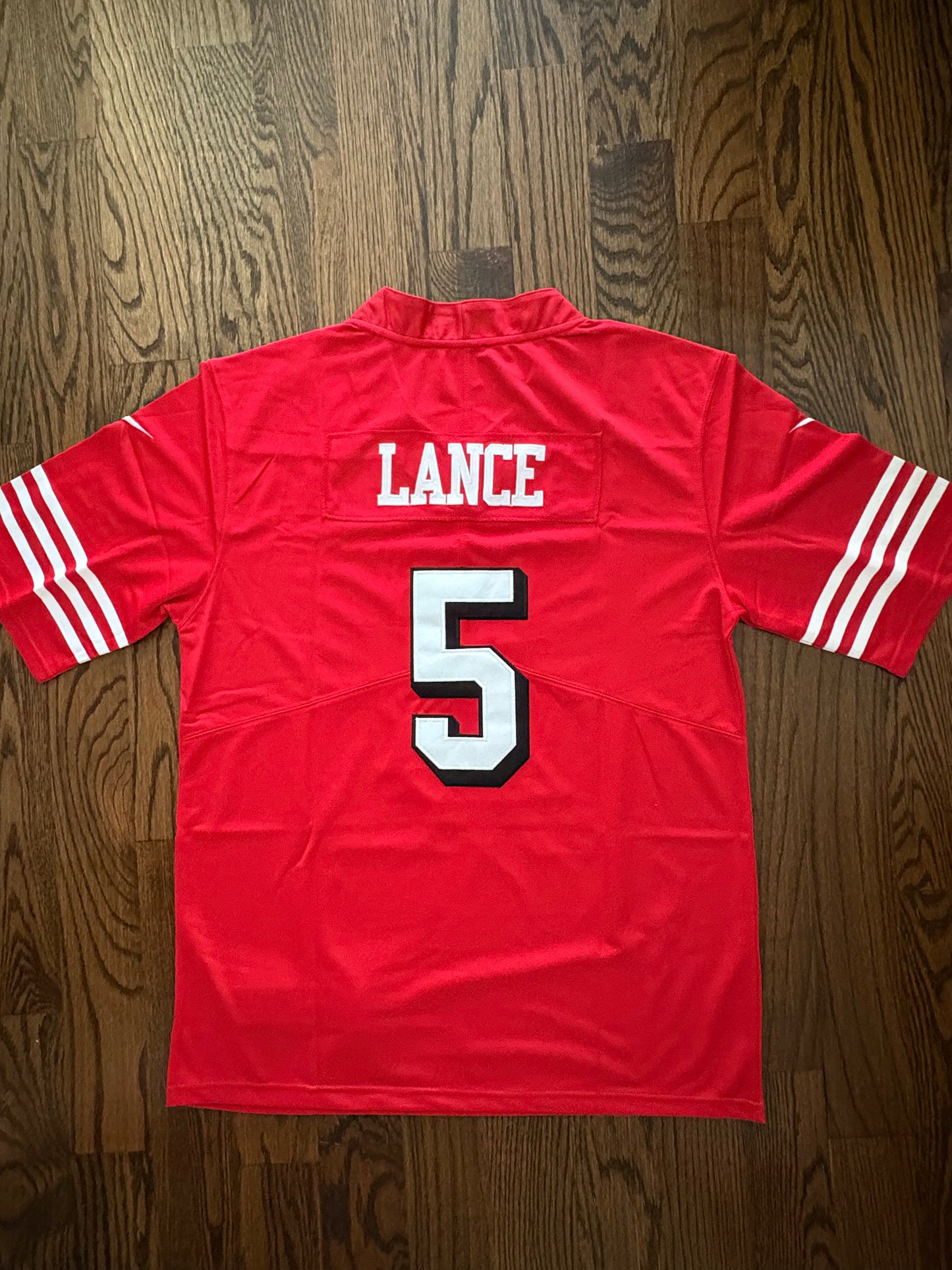 Red sports jersey with 'LANCE' and number '5' on a wooden surface