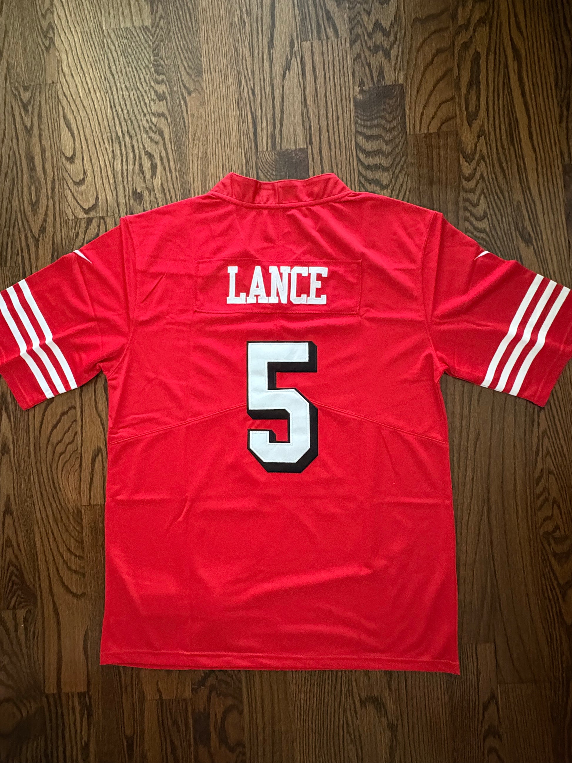 Red sports jersey with 'LANCE' and number '5' on a wooden surface