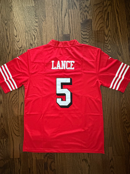 Red sports jersey with 'LANCE' and number '5' on a wooden surface