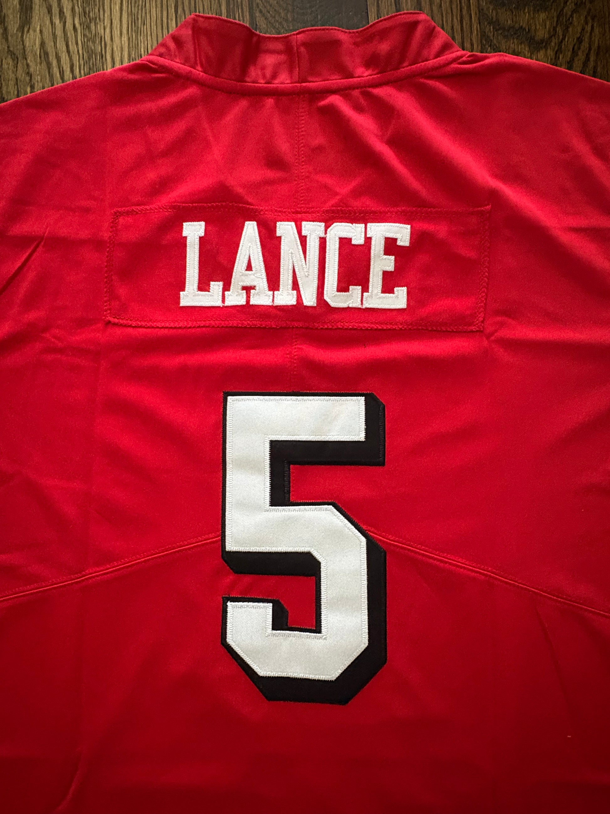 Red jersey with 'LANCE' and number '5' on a wooden surface